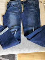 Both pairs of jeans laid flat showing overall condition and distressing
