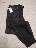 Front view of folded charcoal jeans with tag visible
