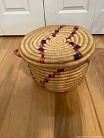 Lidded basket front view showing remaining side handle and dyed pattern