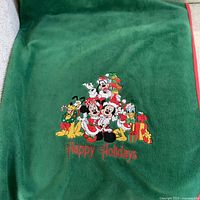 Full view of green Disney holiday fleece throw with character graphic and Happy Holidays text