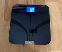 Top view showing black tempered glass scale with blue backlit display reading 0.0