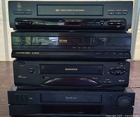 Front view showing all five stacked VCR units with brand names visible