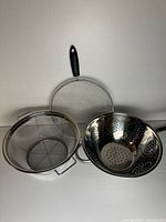 Three stainless steel strainers and colanders