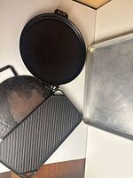 Four cookware pieces arranged: round Camp Chef skillet, round griddle, rectangular ridged griddle, aluminum sheet pan