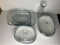 Group shot showing both stoneware dishes with lids, rectangular and square glass dishes, and glass carafe