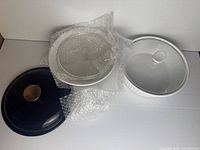 Black metal lid, clear glass lid with white knob, white casserole dish