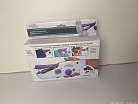 Front of sealed retail box showing handheld fabric fastener tool and bonus snaps