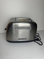 Front view of stainless steel KitchenAid toaster showing brand badge and attached power cord