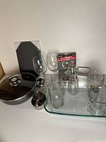 All items grouped: pan with lid, baking dish filled with glassware, syrup dispenser, cutting board, sink strainers, white bowl