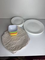 Stack of dinner plates, side plates wrapped, and four colored bowls