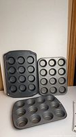 Front view of three 12-cup muffin pans standing upright