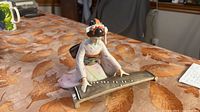 Front view of figurine showing woman in kimono playing koto