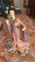 Front view of geisha figurine standing on garden base with lantern and flowers