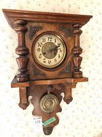 Frontal view of wall clock showing case, dial, pendulum, key tag visible