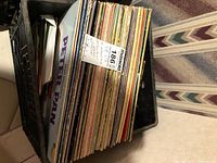 Crate filled with numerous LP records showing colourful edges
