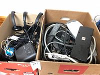 Two boxes with headphones, cables, power strips, white device