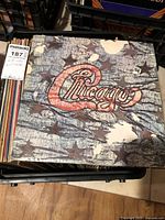 Stack of assorted LPs in crate, top album Chicago with distressed flag design