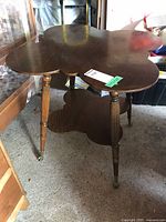 Full view of oak two-tier side table showing top shape, legs, and casters