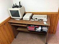 Desk with monitor, computer, disk drive, controllers and storage shelves visible