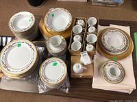 Overall lot showing stacked plates, bowls, cups, chargers and accessory pieces