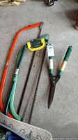 Group shot of three bow saws and hedge shears on garage floor