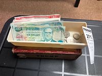 Cigar box with plastic tray holding assorted coins and visible banknotes