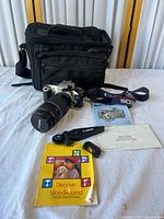 Camera with lens, bag, booklet, strap and accessories overview