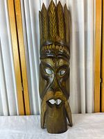 Full view of carved wooden mask showing overall shape and coloration