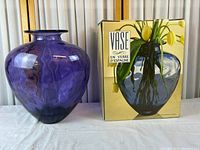 Blue/purple hand-blown glass vase beside retail box showing product image