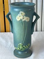 Full view of blue Roseville Primrose vase front showing flower motif and pedestal base