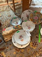 Stack of assorted floral plates and bowls on rug