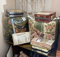 Multiple packaged bedding sets stacked on shelf, showing floral and paisley patterns