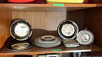 Shelf view showing assortment of Chokin plates, chargers, stacked dinner plates and two Mary Carol trays