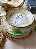 Stack of 7 Kunst Bavaria porcelain plates, lace runner and packaged linens visible