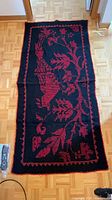 Full view of black runner rug with red botanical pattern and border