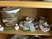 Shelf with stacked plates, teacup, saucer, creamer, sugar bowl, salt & pepper shakers