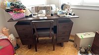 Wide shot of sewing machine, cabinet, chair, case and pedal
