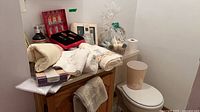 Overview of lot showing towels, perfume sets, basket, wastebasket on toilet lid