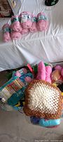 Group of pink skeins on bed and bin with mixed yarn and crocheted granny square