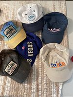 Six assorted baseball caps laid out on table