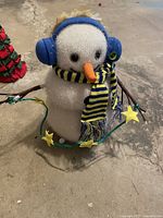 Front view of snowman with earmuffs, scarf and star lights