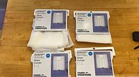 Four packaged Room Essentials sheer curtain panels