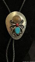 Full view of silver bolo slide with penny, turquoise and red stone on braided cord
