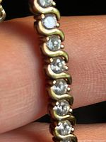 Close-up of bracelet links showing round CZ stones and gold-plated wave settings