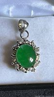 Front view of pendant showing green jade cabochon and surrounding clear crystals
