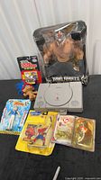 Overview of all items: PlayStation, WWE figure, packaged Speed Racer, Spider-Man, Ty set, loose troll
