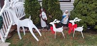 All three white wooden reindeer displayed on lawn; shows relative sizes and red bows on small figures