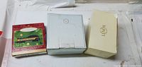 Front view of three boxed Lenox items: red holiday box, light blue box, cream Lenox box