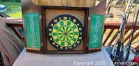 Front view of open wooden cabinet showing dartboard and scoreboards