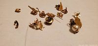 Group of small gold-tone pins and findings spread on surface
